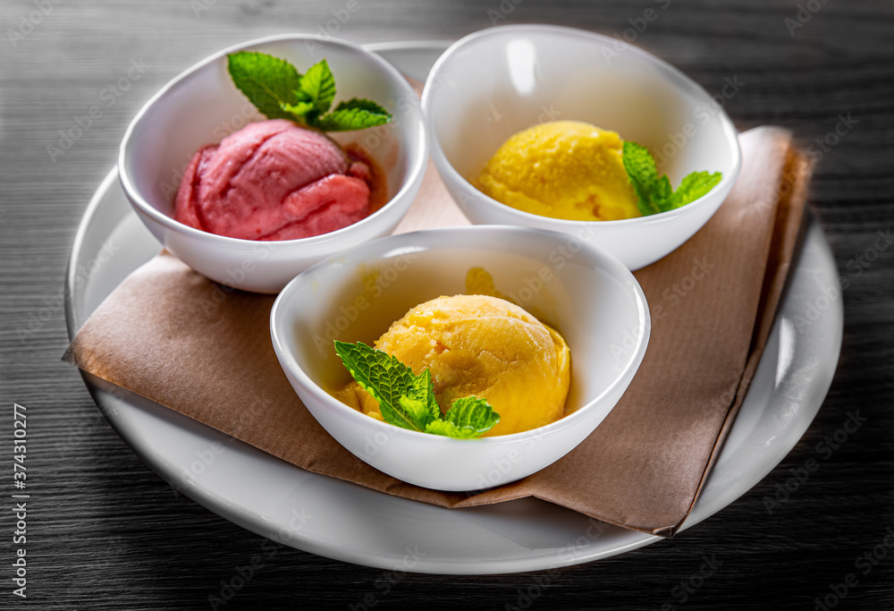 various ice cream desserts with mint leaf on black wooden table various ice cream desserts with mint leaf on black wooden table