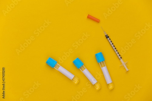 Medical test tubes with syringes on yellow background. Top view