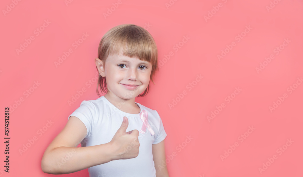.Little girl showing thumb up wearing pink breast cancer awareness ribbon .Little girl showing thumb up wearing pink breast cancer awareness ribbon