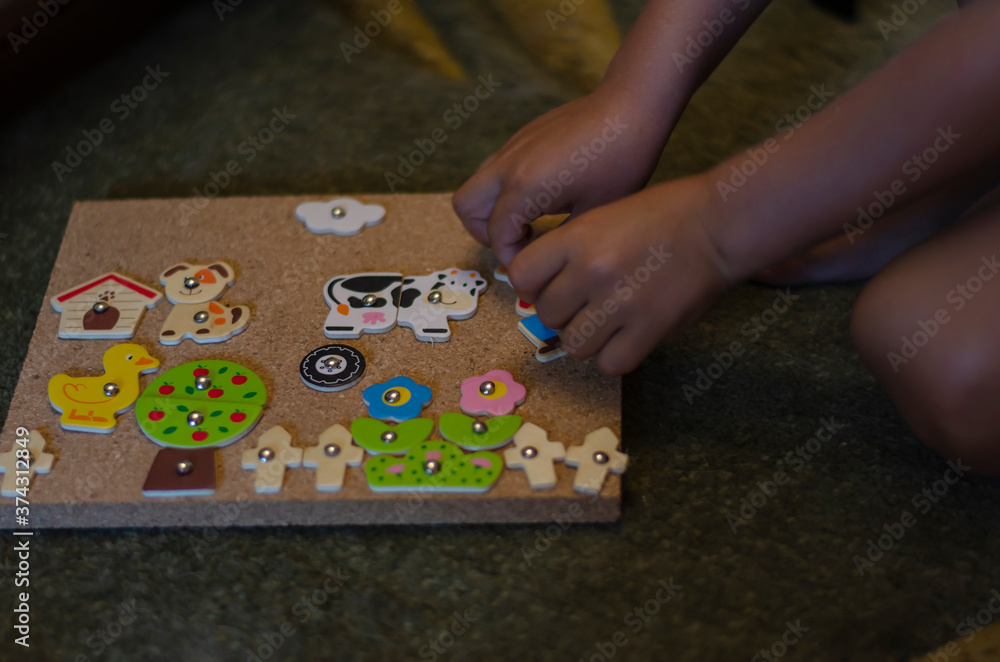 The child plays a board game for children. A preschool boy assembles an applique on the floor indoors. Educational games for children. The child plays a board game for children. A preschool boy assembles an applique on the floor indoors. Educational games for children.