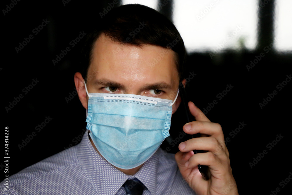 Portrait of man in face mask and office clothes talking on mobile phone, smartphone in male hand close up. Concept of communication during coronavirus pandemic Portrait of man in face mask and office clothes talking on mobile phone, smartphone in male hand close up. Concept of communication during coronavirus pandemic