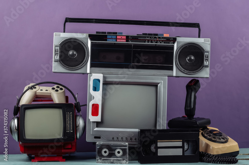 Retro portable mini tv set, radio receiver, record player, headphones, joystick, 3d glasses, gamepad, audio and video cassette, phone on purple background. Attributes 80s, retro media, entertainment