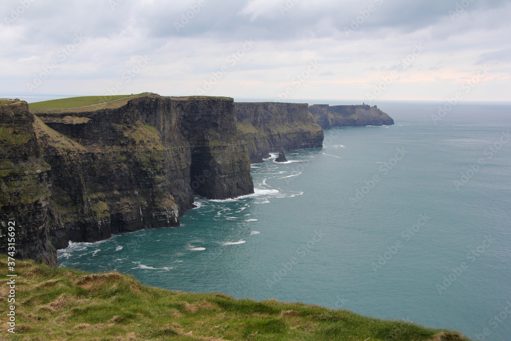 Cliffs of Moher with cloudy skies and vegetation in Ireland