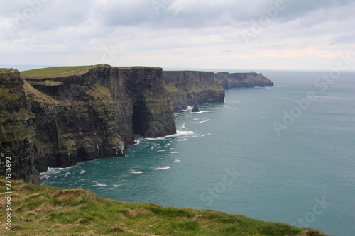 Cliffs of Moher with cloudy skies and vegetation in Ireland