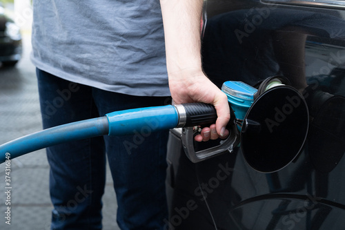 Male hand fills gasoline in a car with gas pump nozzle