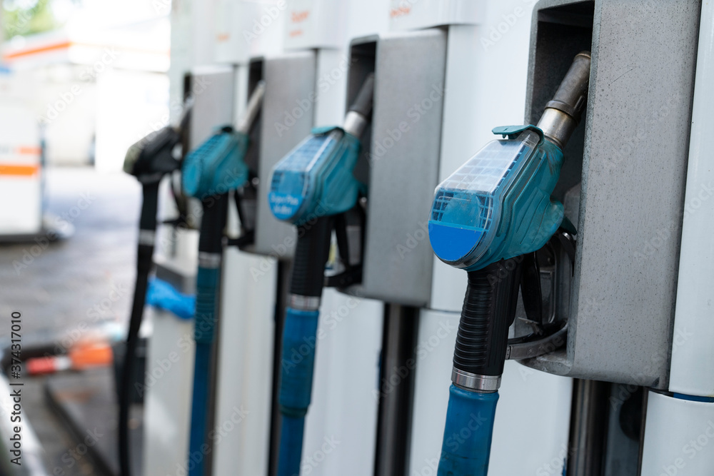 A row with four blue gas pump nozzles A row with four blue gas pump nozzles