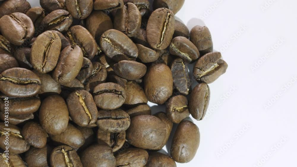 Dark Coffee beans rotating. Close up of roasted coffee beans on white background. Shallow depth of field Dark Coffee beans rotating. Close up of roasted coffee beans on white background. Shallow depth of field