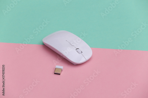 White modern wireless pc mouse on pink blue background.