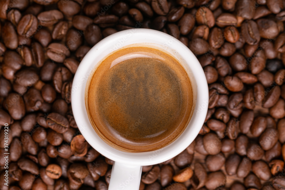 Mugful of coffee in white cup and saucer with coffee grains background Mugful of coffee in white cup and saucer with coffee grains background