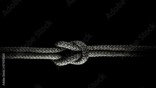 Reef knot black rope on a black background. © Juri