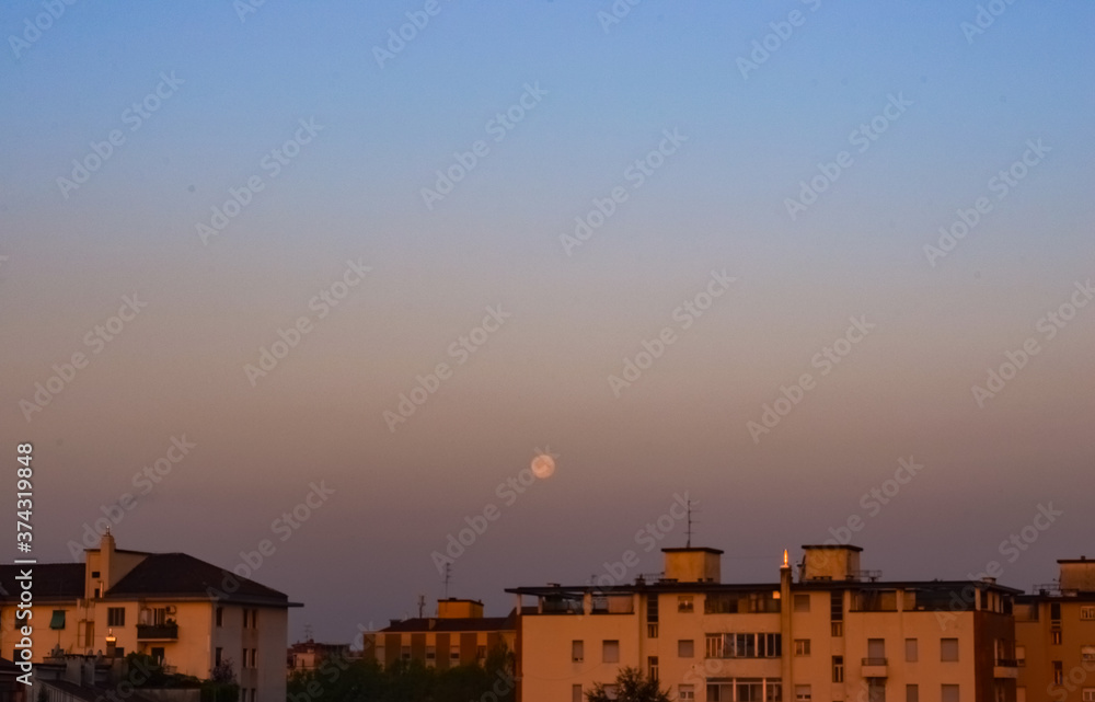 Panoramic city moonset on a beautiful clear gradient coloured sky after sunrise on a summer morning