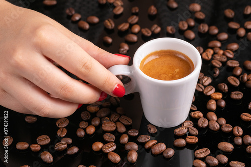 Mugful of coffee in white cup and saucer with coffee grains background photo