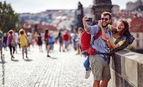 Canvas Print Smiling  man and woman in love walking on a street of Prague city and make selfie