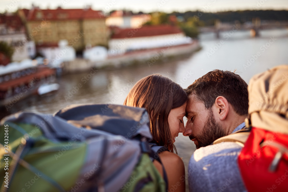 Young man and woman on bridge at Prague kissing at sunset.