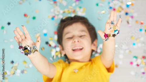 happy birthday child. Photo of charming cute fascinating nice little boy blowing confetti at you to show her festive mood with emotional face expression.