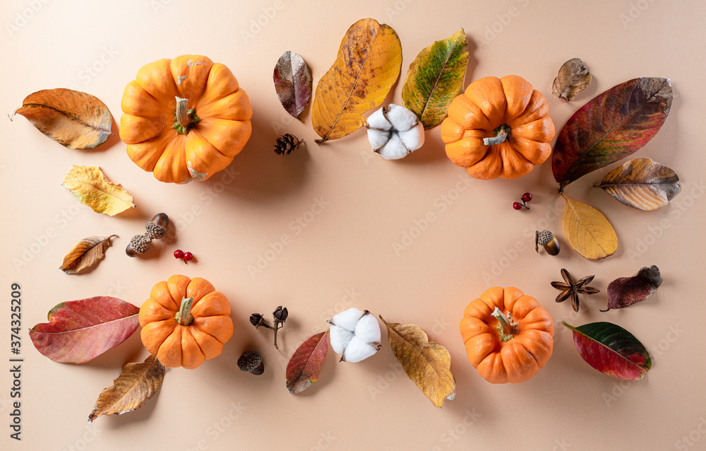 Autumn background decor from dry leaves and pumpkin on pastel paper background. Flat lay, top view with copy space for Autumn, fall, Thanksgiving concept.