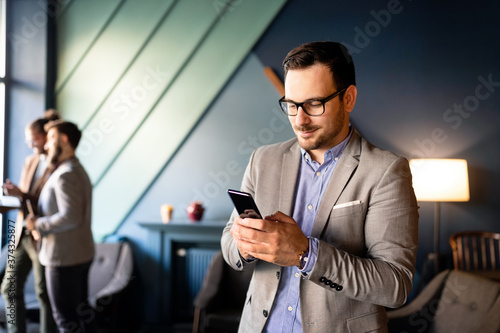 Young handsome businessman using smartphone in the office