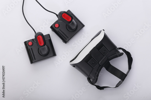 Virtual reality headset and retro joysticks on white background. Entertainment, video game. Top view