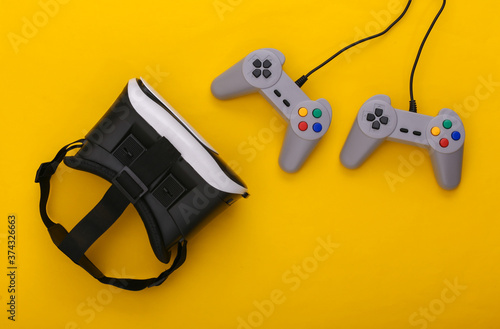 Virtual reality headset, retro gamepads on yellow background. Entertainment, 3d video game. Top view