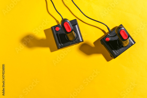 Old joysticks on yellow background with shadow. Retro gaming. Top view