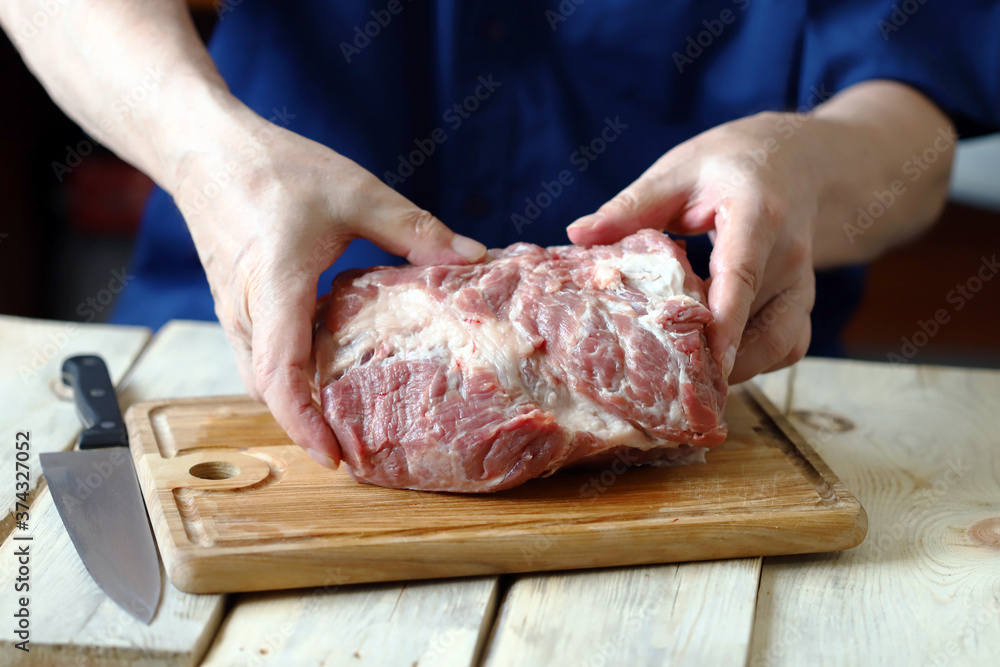 Selective focus. Raw meat in the hands of the chef on a wooden board. Cooking meat.