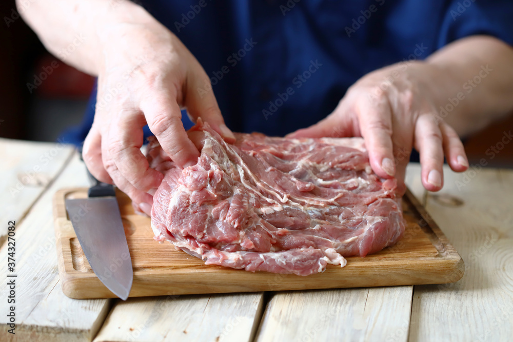Selective focus. Raw meat in the hands of the chef on a wooden board. Cooking meat.