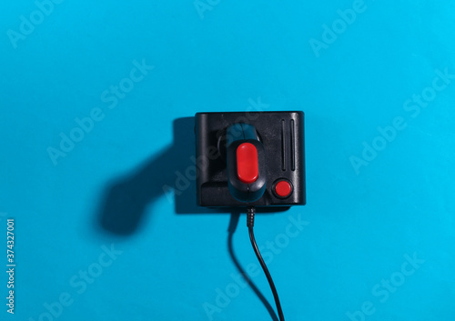 Retro joystick on a blue background with a shadow. Retro gaming. Top view