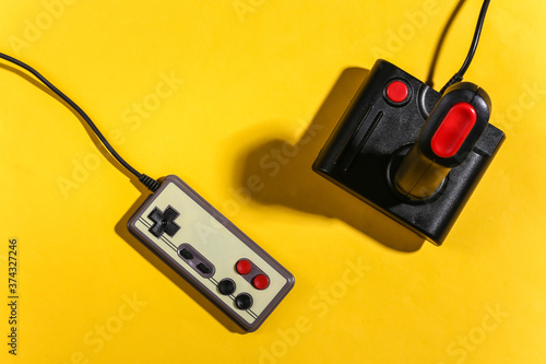 Retro joystick and gamepad on yellow background with shadow. Retro gaming. Top view