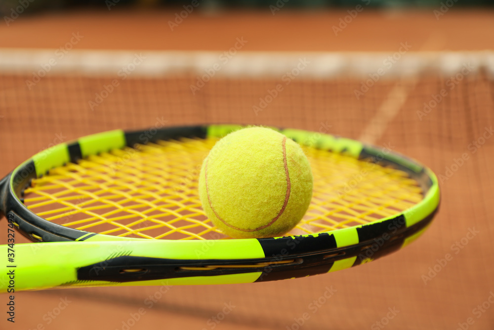 Tennis racquet with tennis ball against clay court