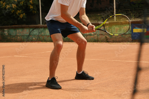 Young man playing tennis on clay court © Atlas