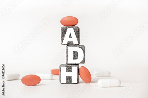 a group of white and red pills and cubes with the word ADH Antidiuretic hormone on them, white background. Concept carehealth, treatment, therapy. photo