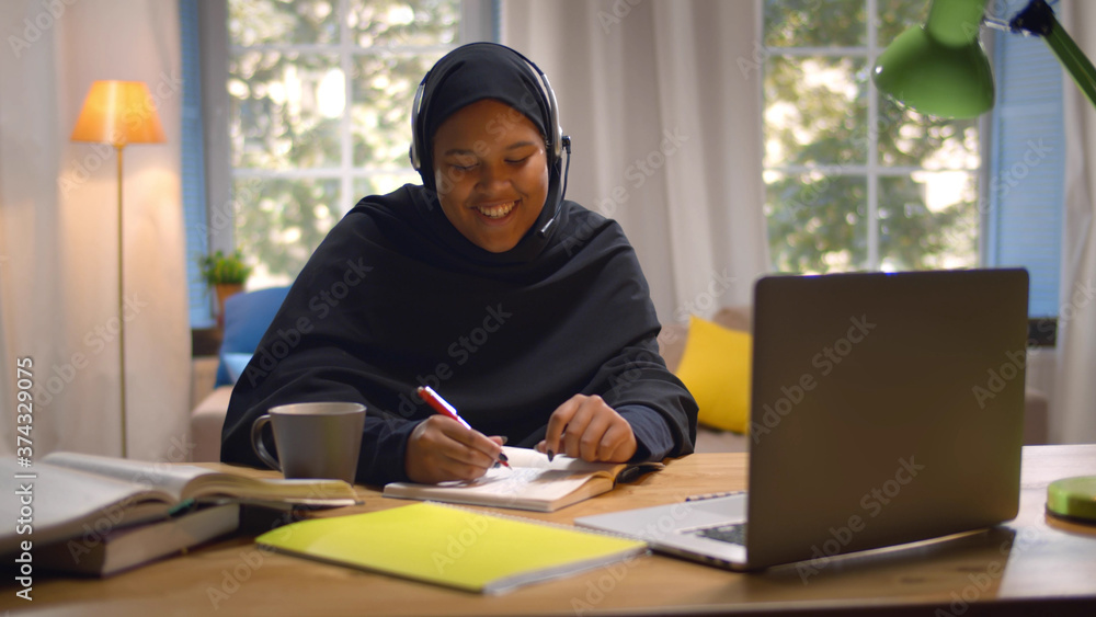 Fototapeta premium Happy Arabic Girl In Headscarf And Headset Studying With Laptop At Home