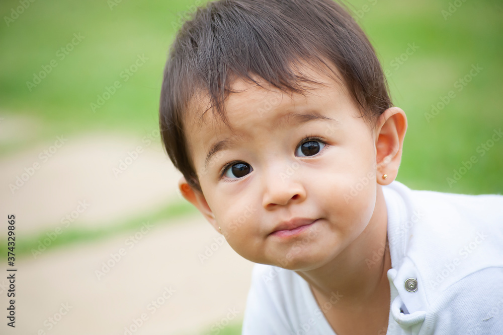 .Portrait of 1 year old Asian-looking girl playing alone in the yard. Outdoor scene. Selective focus. Copy space .Portrait of 1 year old Asian-looking girl playing alone in the yard. Outdoor scene. Selective focus. Copy space