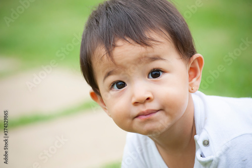 .Portrait of 1 year old Asian-looking girl playing alone in the yard. Outdoor scene. Selective focus. Copy space