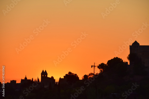 Orange sunrise behind the buildings of a village on a summer day