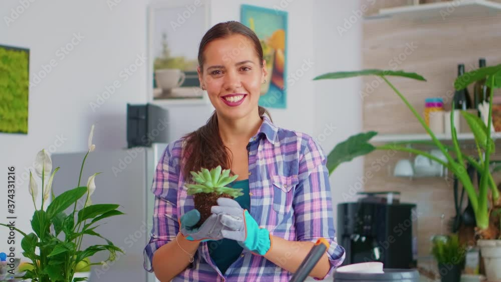 Closeup of portrait woman smiling and holding flower. Florist replanting flowers in ceramic pot using shovel, gloves, fertil soil and flowers for house decoration. Closeup of portrait woman smiling and holding flower. Florist replanting flowers in ceramic pot using shovel, gloves, fertil soil and flowers for house decoration.
