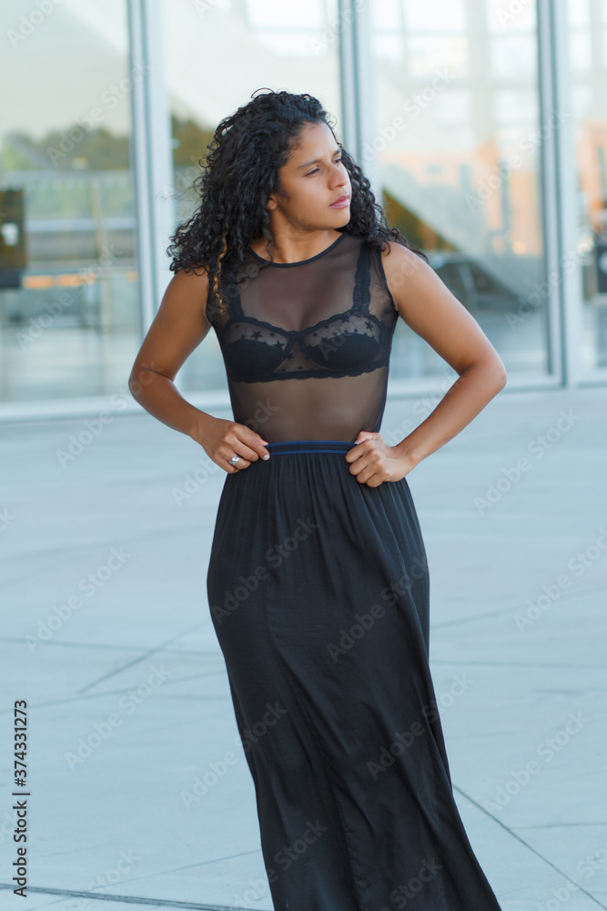 joven mujer de cabello negro rizado posando en la ciudad 