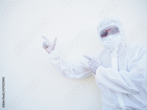 Asian male doctor or scientist in PPE suite uniform showing pointing two fingers away at copy space while standing and looking forward. coronavirus or COVID-19 concept isolated white background
