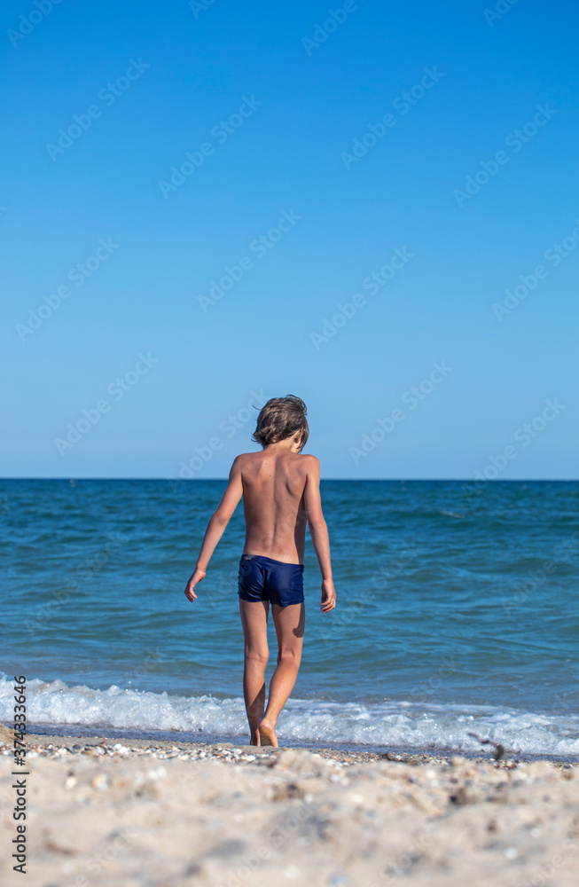happy boy walks into the sea, vertical format happy boy walks into the sea, vertical format