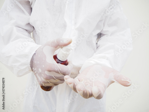 Portrait of doctor or scientist in PPE suite uniform holding plastic bottle with skin care product. COVID-19 concept isolated white background
