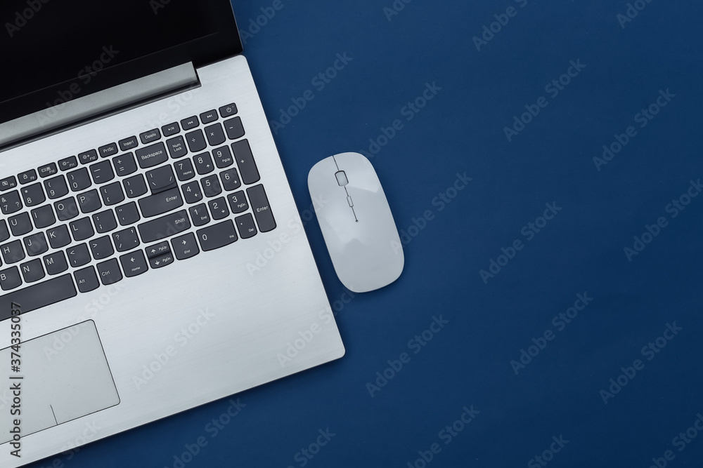 Laptop with pc mouse on classic blue background. Online workspace. Remote work. Studio shot. Color 2020. Top view. Flat lay - obrazy, fototapety, plakaty 