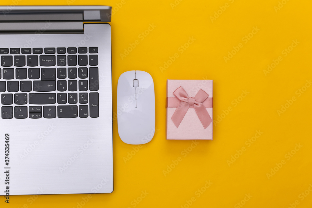 Online shopping. Laptop with pc mouse, gift box on yellow background. Top view. Online shopping. Laptop with pc mouse, gift box on yellow background. Top view.