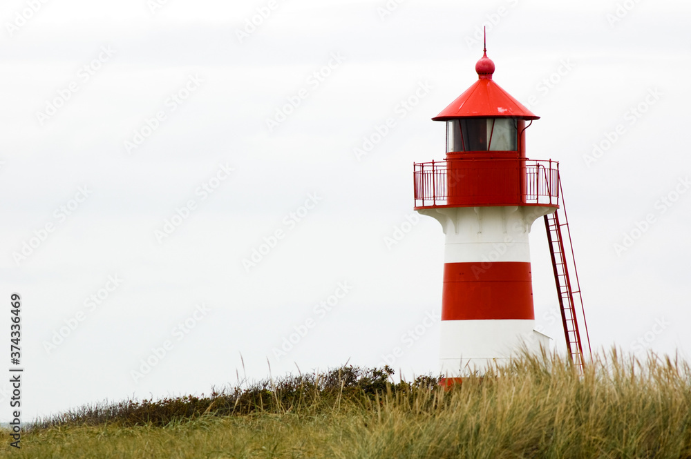 Red and white lighthouse in Denmark in the dunes Red and white lighthouse in Denmark in the dunes