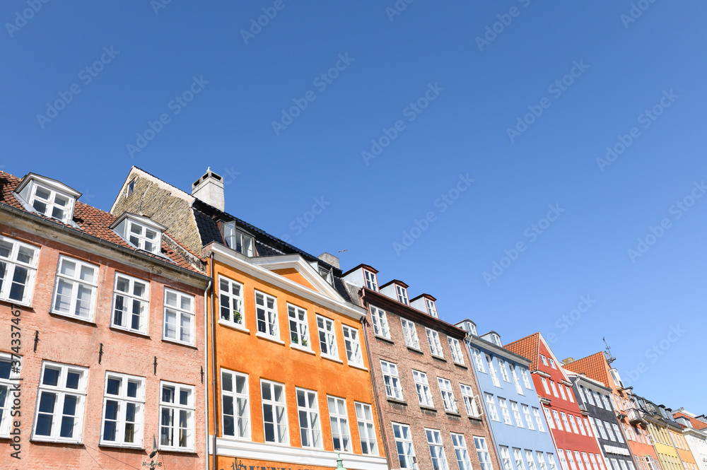 COPENHAGEN, DENMARK 29. June 2019: The colorful houses of the Nyhaven in Copenhagen Denmark on a sunny day with a bright blue sky.