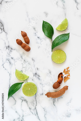 Fototapeta Naklejka Na Ścianę i Meble -  Flat lay mock up with sweet tamarind and green lemon on a marble background suitable for cosmetics advertising