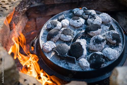 Dutch oven cooking in a campfire with glowing coal on the top photo