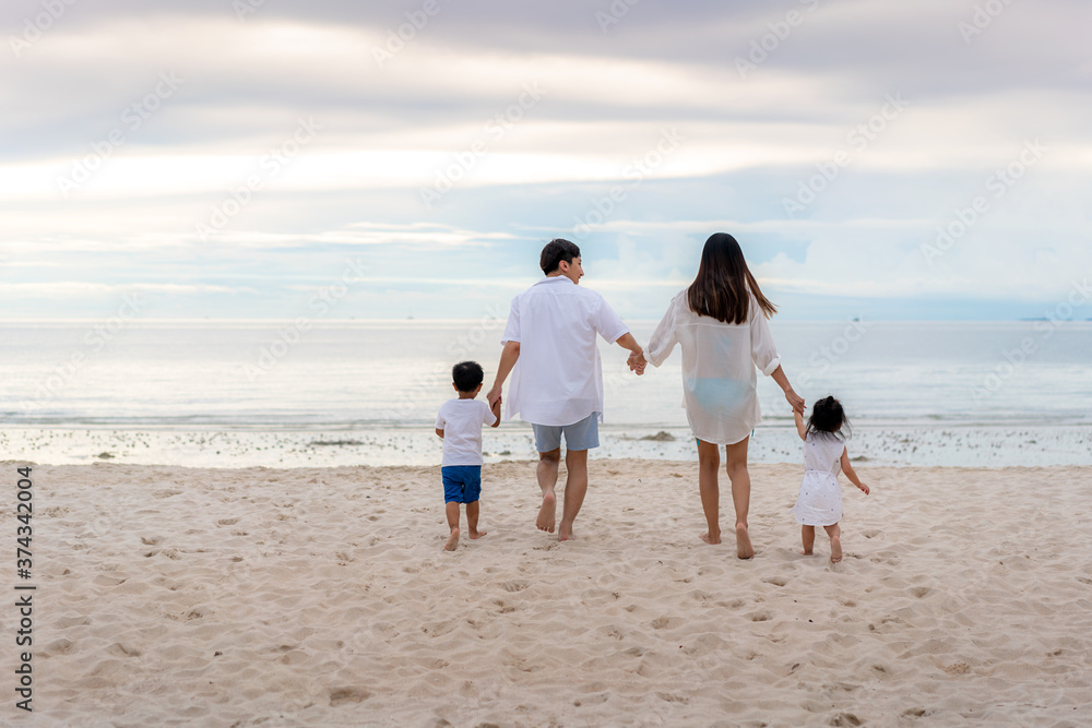 Happy Asian family holidays during joyful father, mother, son and daughter walking together along summer sunset sea. Happy family travel on beach in holiday, Summer and vacation. Happy Asian family holidays during joyful father, mother, son and daughter walking together along summer sunset sea. Happy family travel on beach in holiday, Summer and vacation.