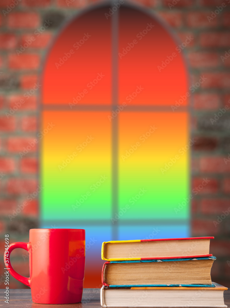 Fototapeta premium books and a red cup on the table, against the background of the window