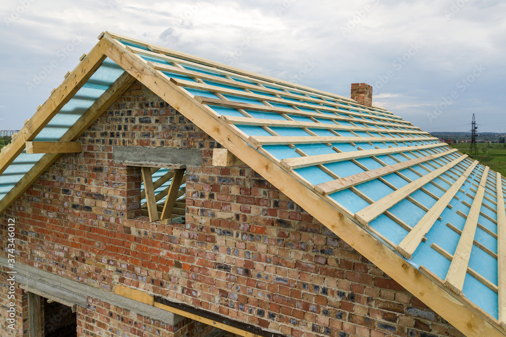 Aerial view of a brick house with wooden roof frame under construction. Aerial view of a brick house with wooden roof frame under construction.