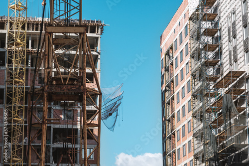 tower crane at a building site during the construction of blocks of flats. Detail of residential building under construction. Concrete structure with metal struts.  © kseniaso